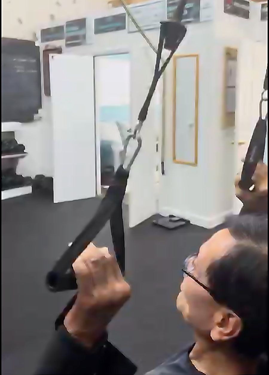 Senior client doing a cable row during a personal training session